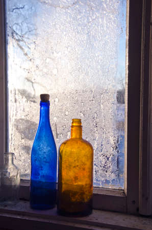 two old vintage bottle on frosty farm winter windowの写真素材