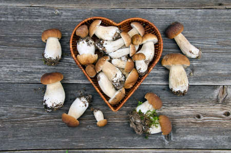 edible mushroom fungi boletus in heart form basket on old wooden tableの写真素材