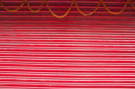 red painted corrugated metal door and flowers garland backgroundの写真素材