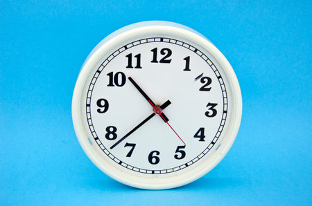 white clock dial clock-face with black arrows on blue background