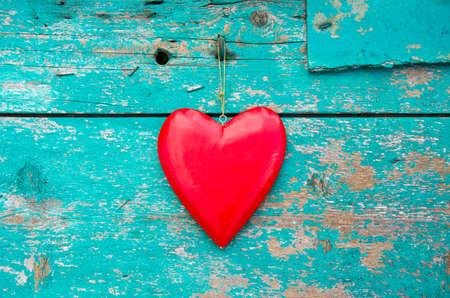 hang red wooden heart symbol on old grunge green house wallの写真素材