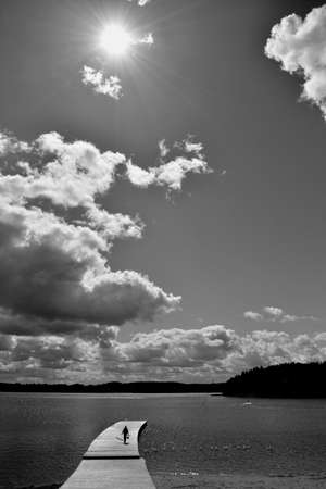 Black and white resort landscape with lake and human walking on wooden bridgeの写真素材