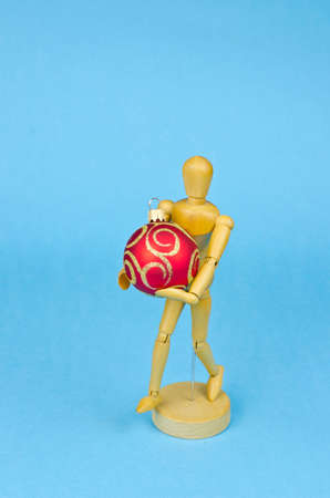 One wooden artist manikin with red christmas bauble on blue azure backgroundの写真素材