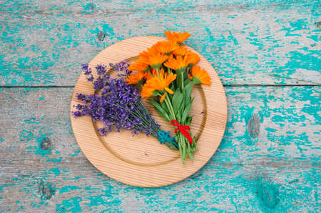 marigold and lavender bunch in wooden plate on farm tableの写真素材