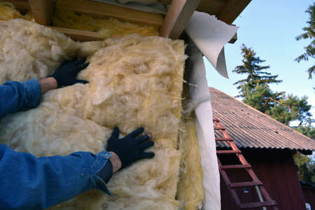 Farmer worker hands insulating with rock wool wooden house wallの写真素材