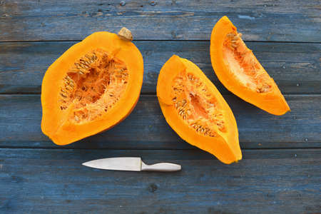 Fresh ripe yellow  pumpkin cuts on garden table and knifeの写真素材