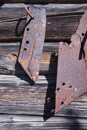 Old rusty plow detail  blade on gray wooden barn wall backgroundの写真素材