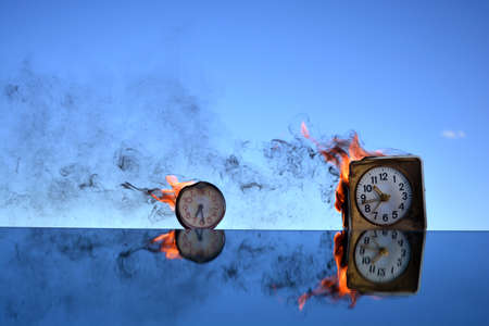 Two antique old clock burning in space on mirror, time conceptの写真素材