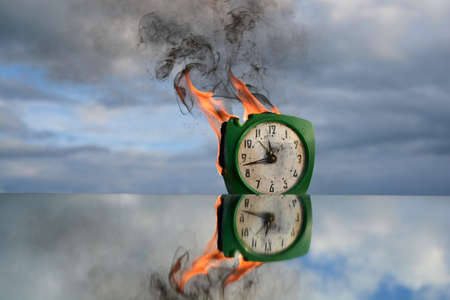 Burning old green clock on mirror in space, time is a fireの写真素材