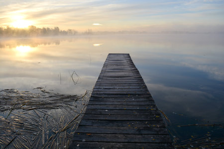 Old wooden lake bridge and autumn morning mist, lake landscape  の写真素材