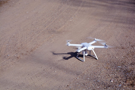 New white drone with camera on gravel road in motion