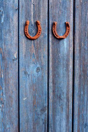 Two pair old rusty hotseshoe lucky symbols on old blue wooden house wall