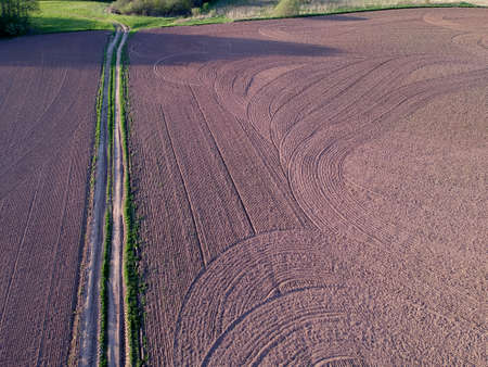 cultivated spring agriculture field and farm road, aerialの写真素材