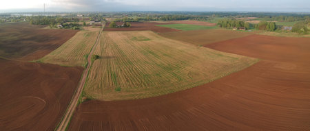 Cultivated sowed spring farmland fields and bad road, aerial