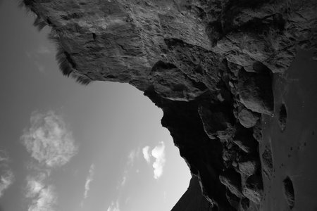 A black and white of the cliff face and sky at Hamilton gap beach in Auckland, New Zealand.