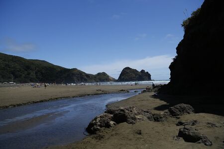 Beach view at phia beach in Auckland, New zeland.  A stream going into the sea with land, sand and sky.の写真素材