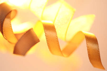 Gold colored curling ribbons with a light behind them.の写真素材