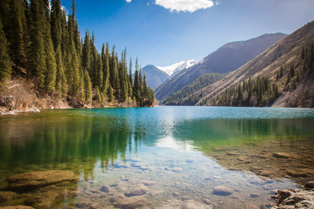 Majestic mountain lake with green trees in Kazakhstanの写真素材