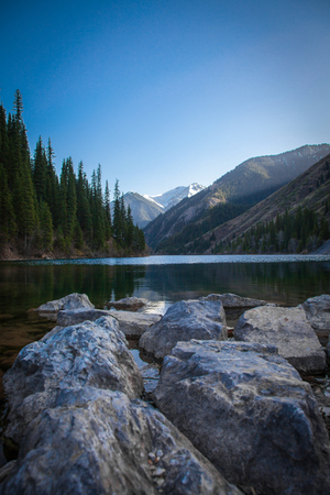 Majestic mountain lake with green trees in Kazakhstanの写真素材