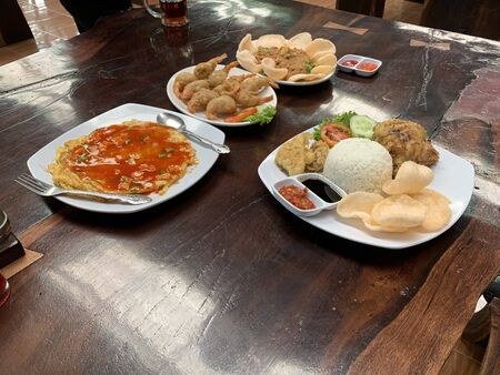 A different dishes of Indonesian national cuisine on top of a wooden table topped with plates of food. High quality photoの写真素材