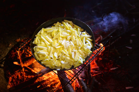 Pan fried potatoes with onions on a fire on a picnic