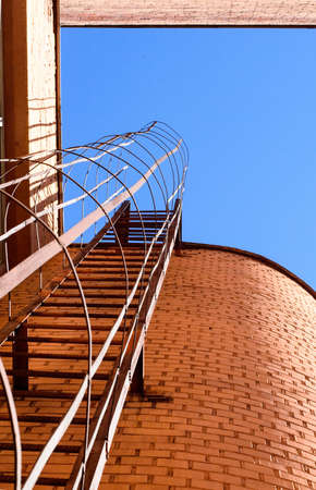 Industrial ladder, blue sky and brick walls of the building, bottom view.の写真素材