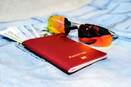 Red russian Passport with money bills and glasses on jeans. The concept of travelの写真素材