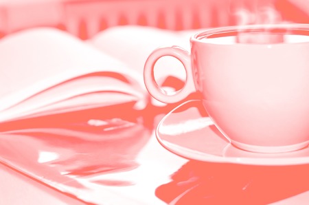 Living coral color of the Year 2019. Cup of coffee on the desk in the office. Retro tonedの写真素材