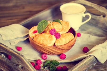Croissants with raspberries on a wooden tray. The concept of a wholesome breakfastの写真素材