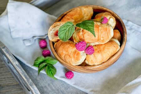 Croissants with raspberries on a wooden tray. The concept of a wholesome breakfastの写真素材