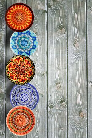 Vertical Set of decorative ceramic plates hand painted dot pattern with acrylic paints on a gray wooden background. Copy spaceの写真素材