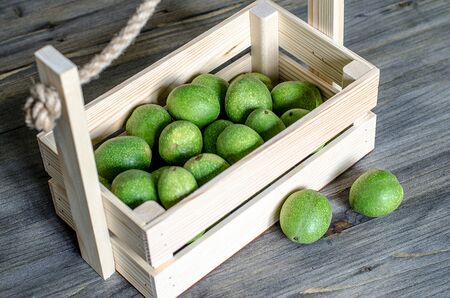 Young fruits of walnuts in a green shell in a wooden boxの写真素材