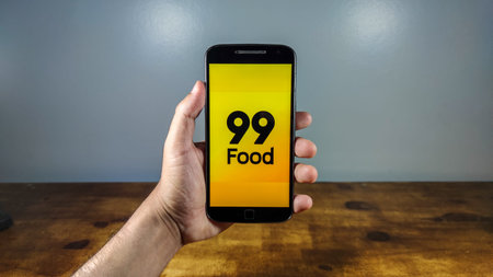 Delivery 99 food. Smartphone with 99 food logo on it. 99 food is a company in the segment of food...