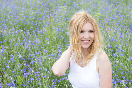 Portrait of young beautiful smiling woman on background of cornflowersの写真素材