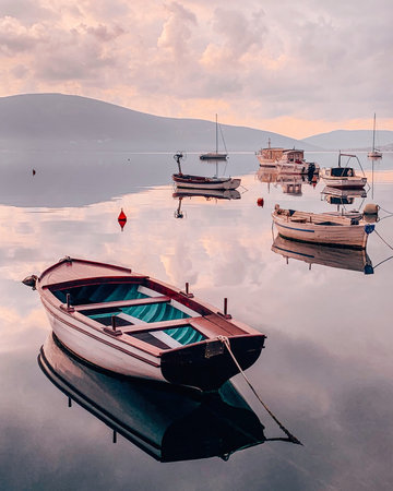 Boats reflecting in the calm sea in beautiful pink sunset. Montenegro seascape.