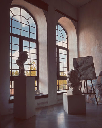 Contemporary art gallery interior with high arched windows, sculptures and painting. Interior of an artist's studio.の写真素材