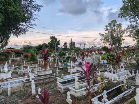 Muslim Cemetery with white headstones, concrete enclosures, and vibrant plants, reflecting cultural burial traditions in a serene settingの写真素材