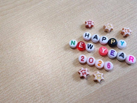 Beads and cartoon star shapes spell âHAPPY NEW YEAR 2026â on woodの写真素材