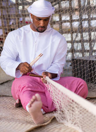 Man Making traditional fishing net in qasr al hosn festival in Abu Dhabi in February 15, 2015のeditorial素材