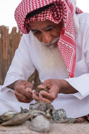 An old man opens the shellfish in SHEIKH ZAYED HERITAGE FESTIVAL september 22, 2014 in Abu Dhab, united arab emiratesのeditorial素材