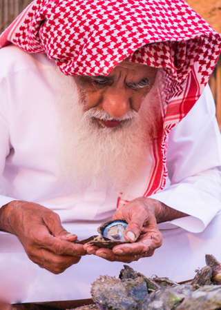 An old man opens the shellfish in SHEIKH ZAYED HERITAGE FESTIVAL september 22, 2014 in Abu Dhab, united arab emiratesのeditorial素材