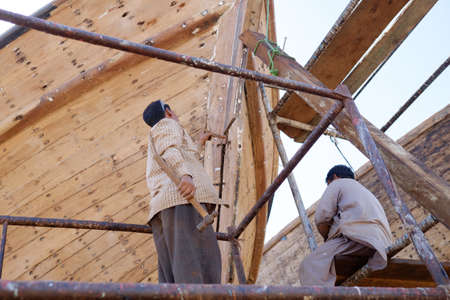 Indian and Bengali Workers repairing old wooden ships and Dhows cruise in Dubai, UAE on 13.10.2014のeditorial素材