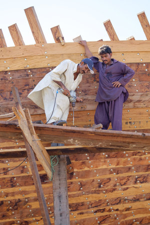 Indian and Bengali Workers repairing old wooden ships and Dhows cruise in Dubai, UAE on 13.10.2014