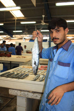 Young man hold a fish in Dubai fish market , Dubai, United Arab Emirates on 03 October 2010のeditorial素材