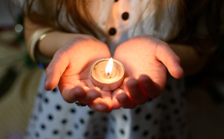 Burning candle in the palms of a girlの写真素材