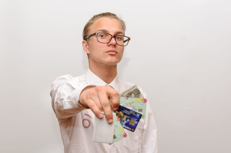 A young man in glasses holds bank cards in his hand.