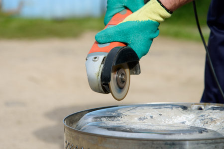 Worker cuts in metal with an angle grinder
