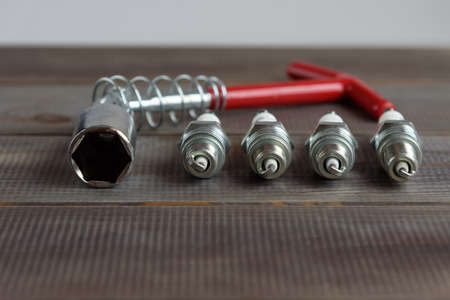 Car spark plugs and key on a wooden tableの写真素材