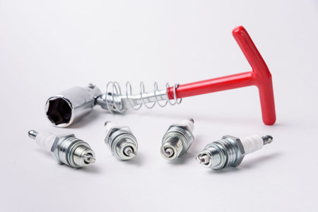 Car spark plugs and key on white