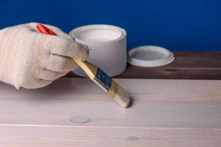 Painting the board with white paint. A can of paint and a brush on a wooden table.の写真素材